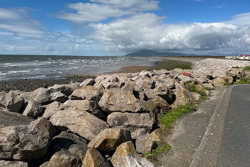 A landscape photograph overlooking a stone wall to the sea and horizon beyond.