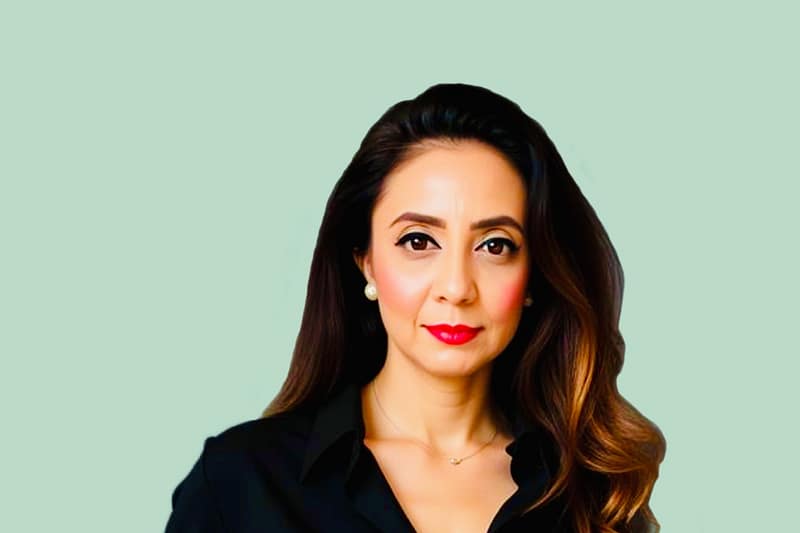 Dr Khyati Rawal, against a green background, looking at the camera.